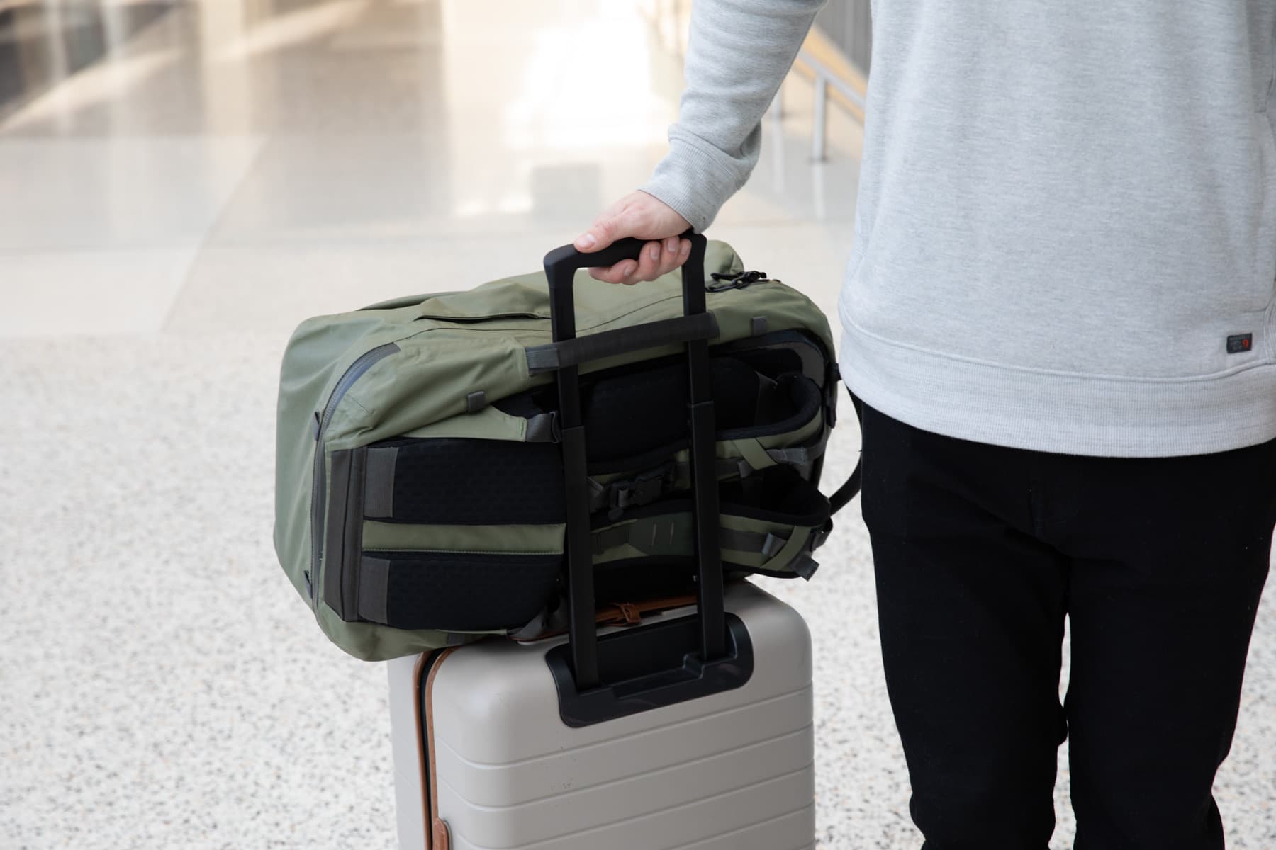 A man with his Errant Pro backpack strapped to his carry-on luggage.