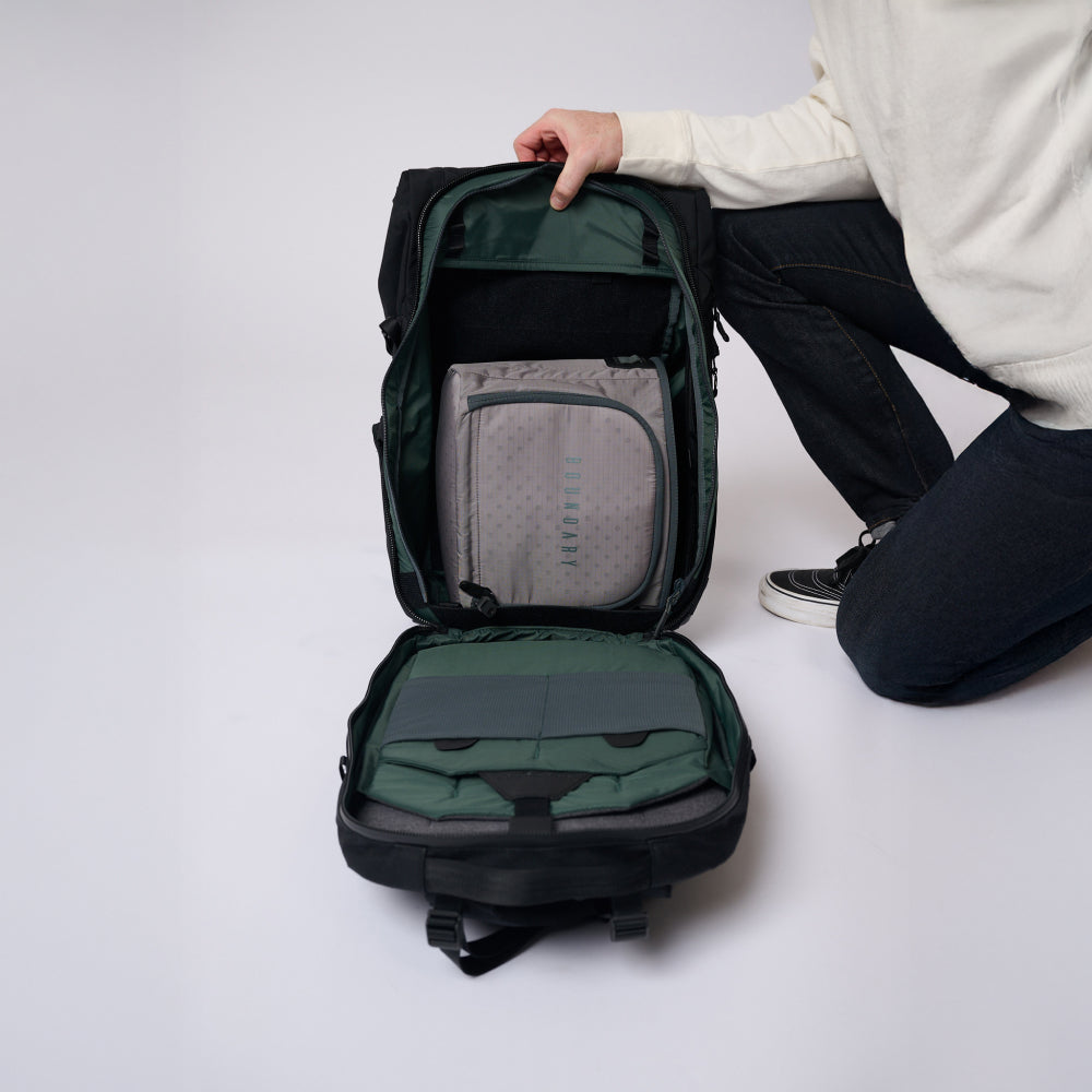 Person opening a green backpack on a white background