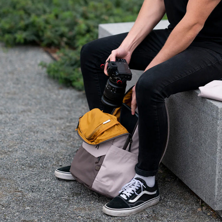 A man slides his camera into his Rennen Recycled Daypack.
