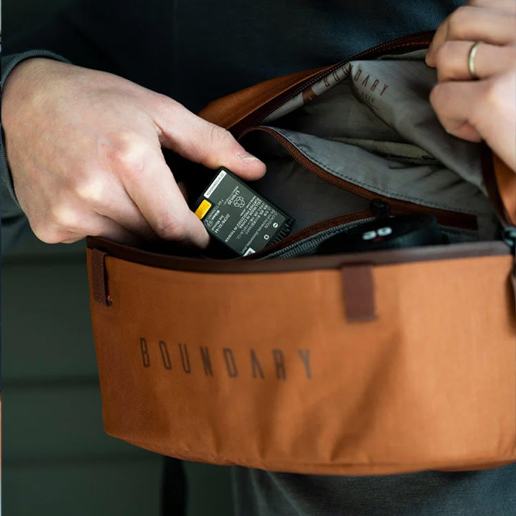 An individual inserts a small camera item into the Boundary Supply waist pack.