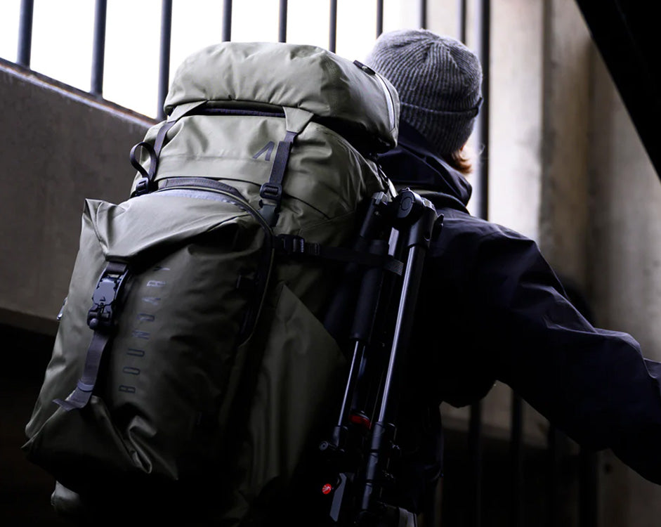 A man climbs a stairway in a parking garage, with a Boundary Supply backpack.