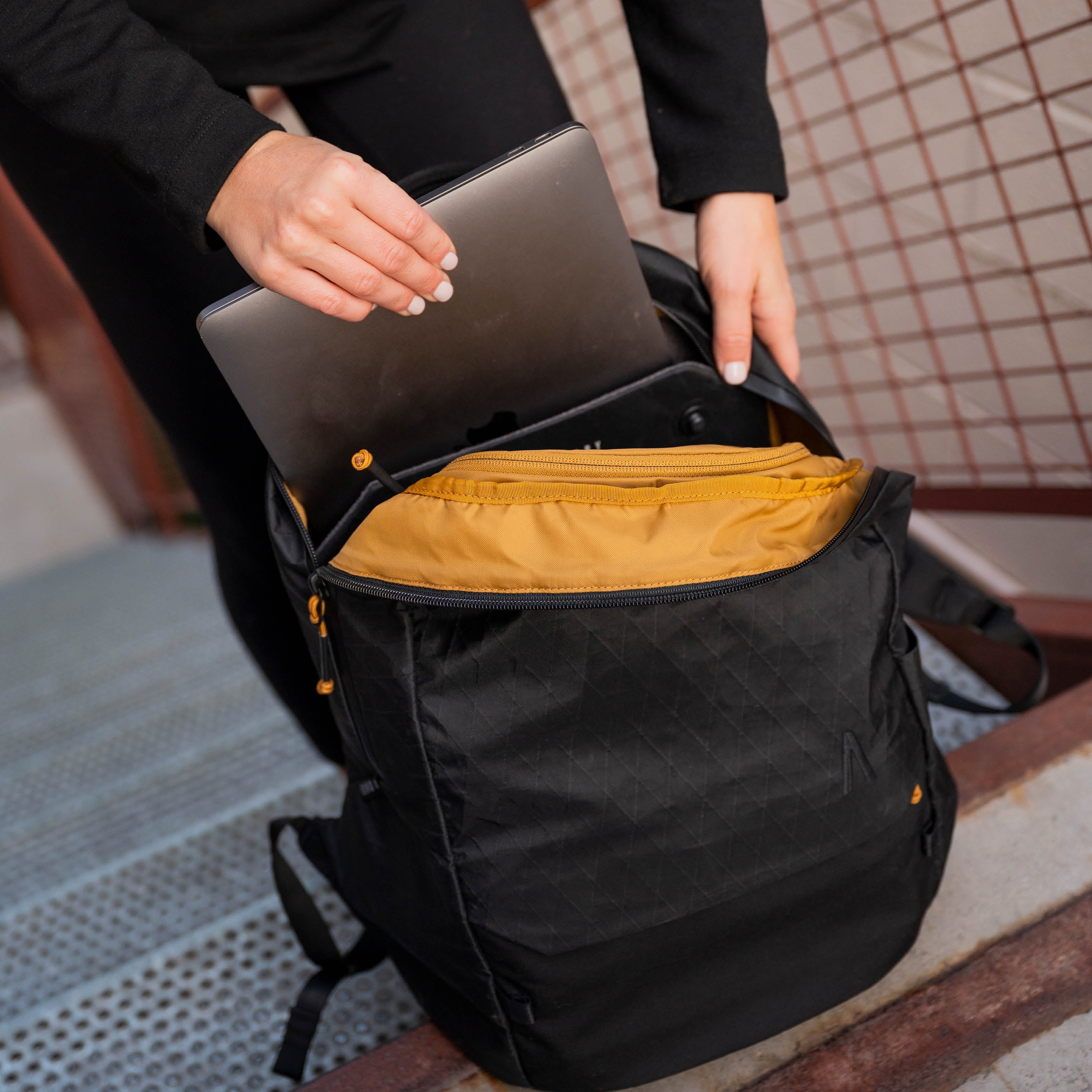A woman inserts a laptop into her Rennen X-Pac Daypack.