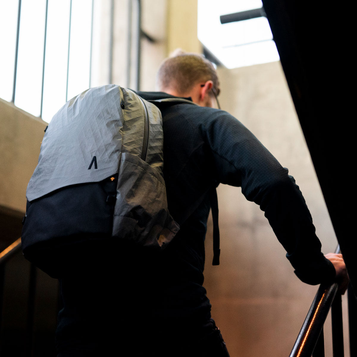 A man climbs a set of stairs with his Rennen Daypack X-Pac.