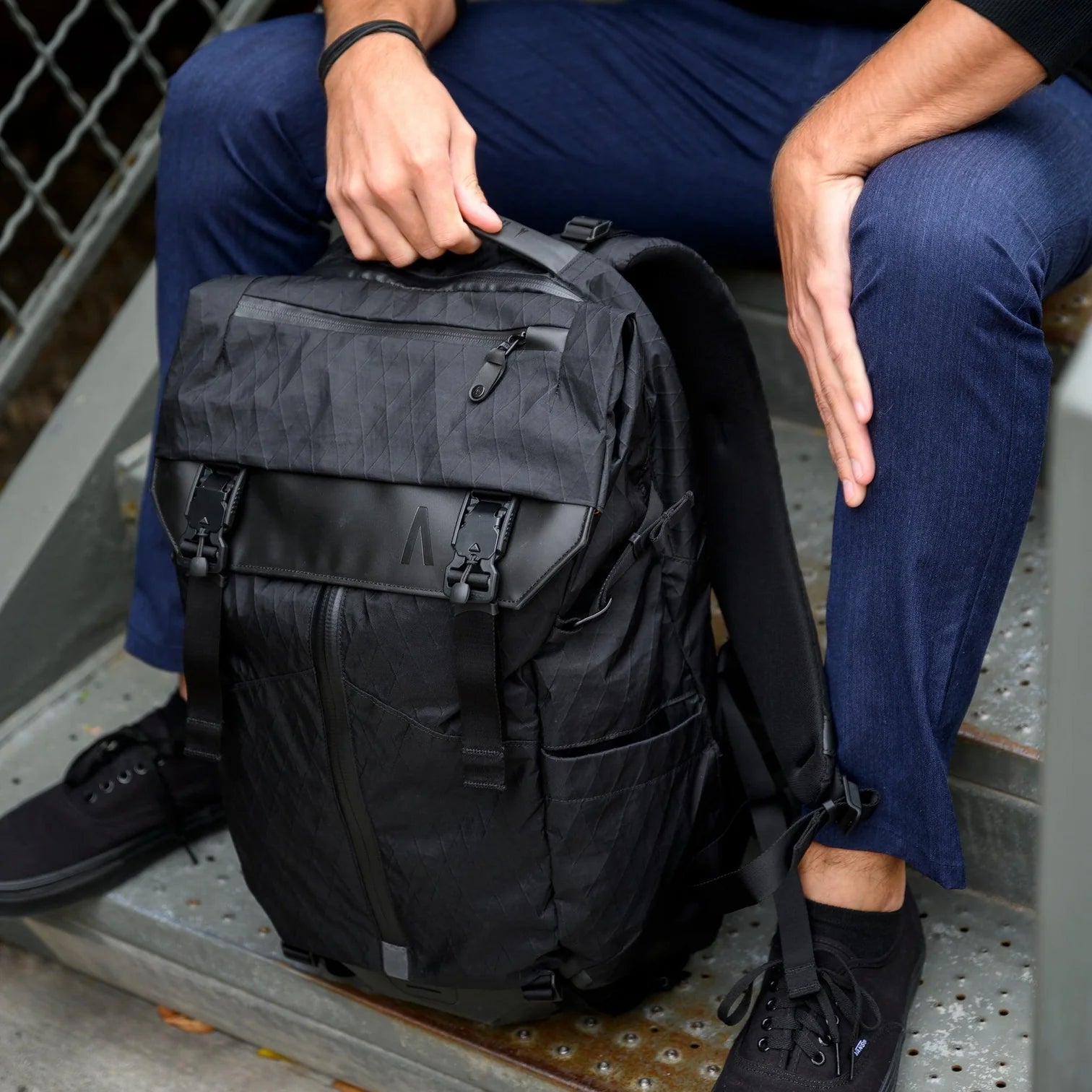 Man holding black Boundary Supply laptop backpack on stairs