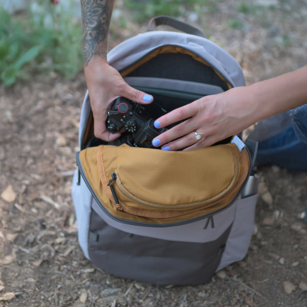 Person placing a camera into a backpack outdoors