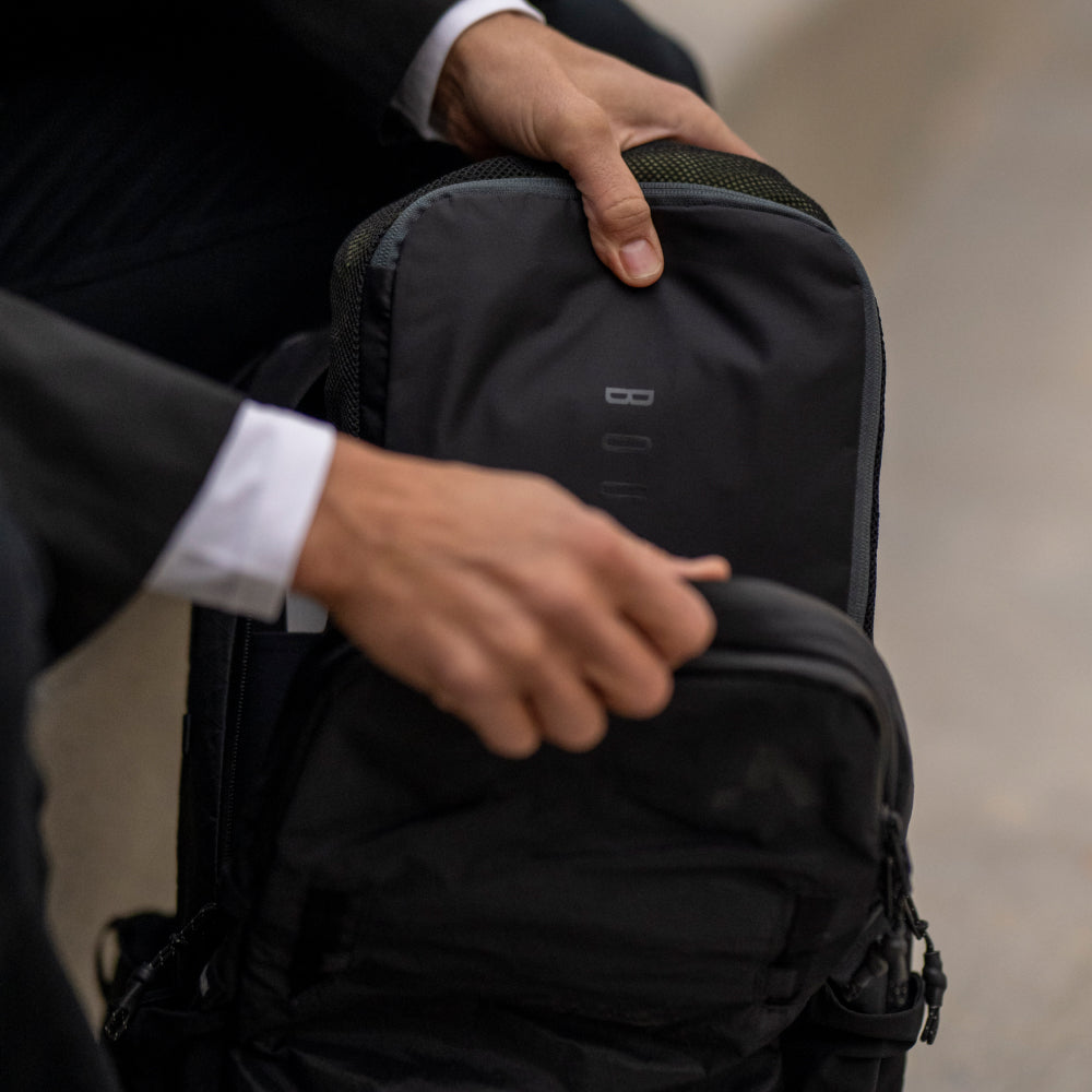 Person holding a black backpack with a blurred background