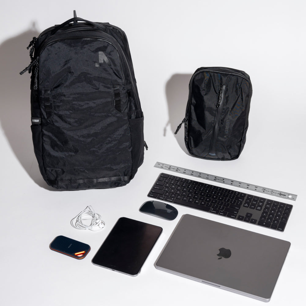 Black backpacks and electronic devices on a white background