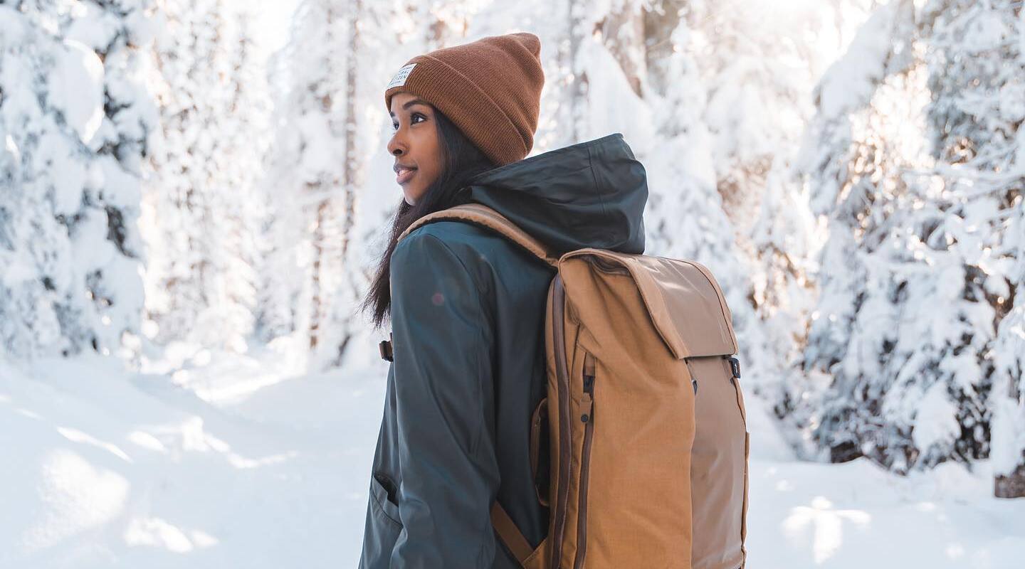 A woman wearing a waterproof camera backpack in a snowy landscape